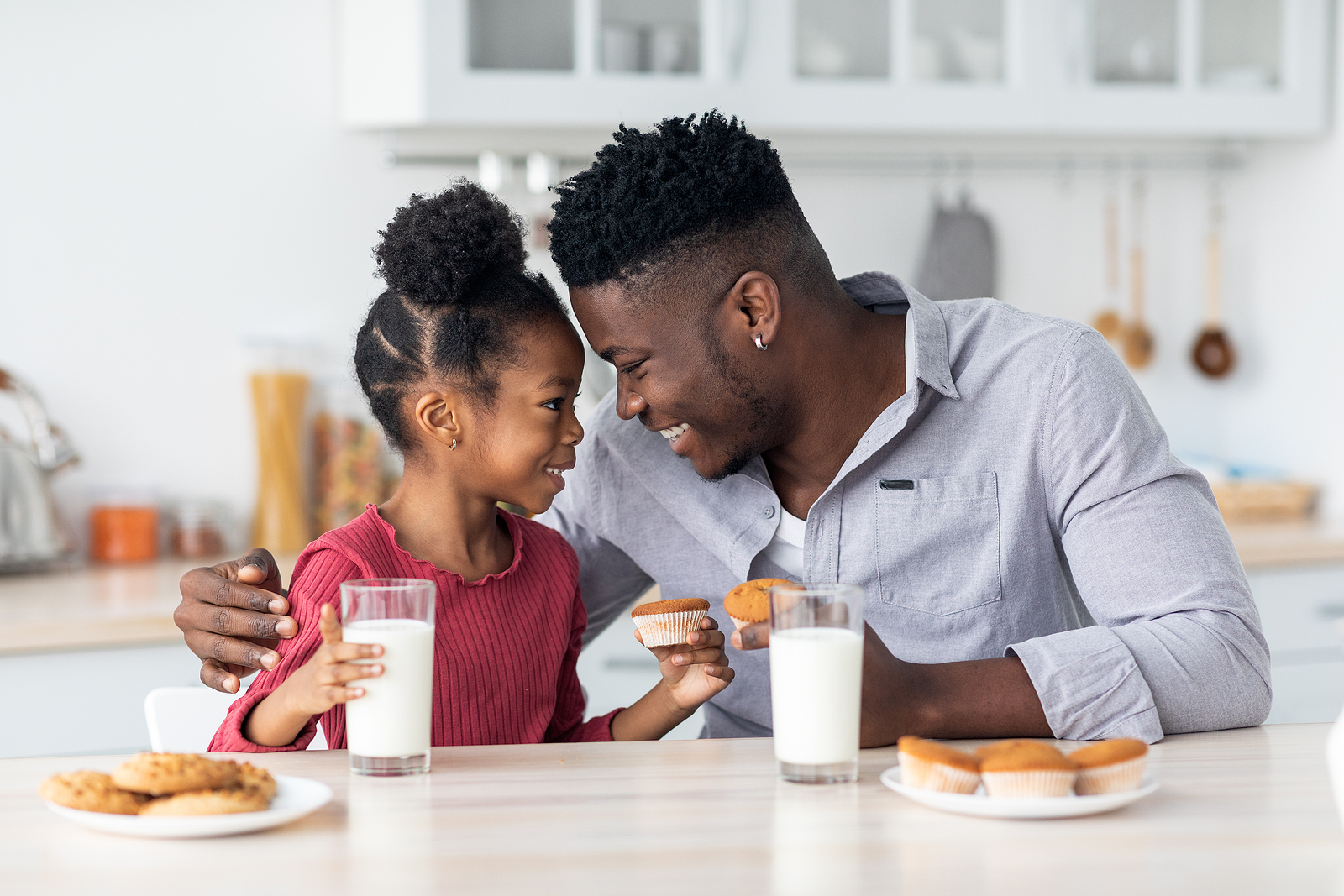 Una niña con su papá compartiendo un vaso de leche Image